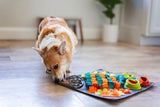 Cute corgi licking of the integrated silicone lick mat eyeing up treats in the forage portion of the mat. 